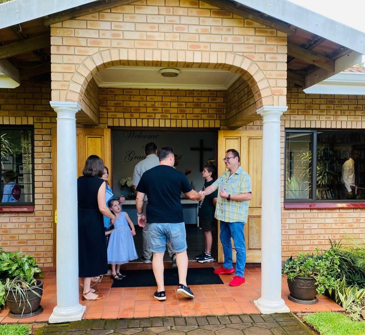 Members greeting a family at the front doors of the church